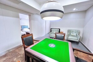 Une pièce comprenant une table de billard, deux fauteuils, un lit et un luminaire fixé au plafond.