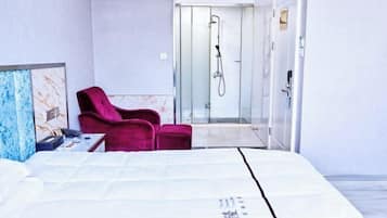Una habitación de hotel con cama, una silla roja y zona de ducha.