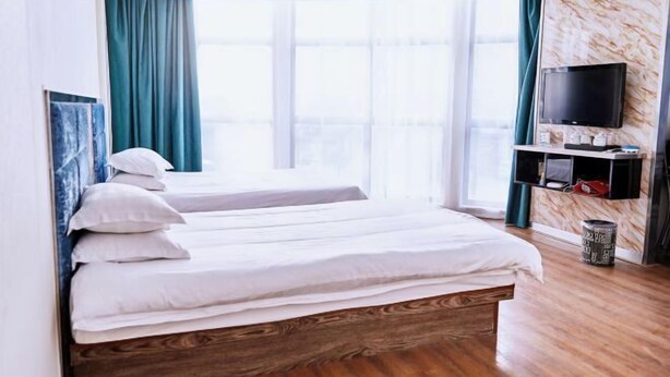 Een hotelkamer met een bed, een televisie en een raam met gordijnen.