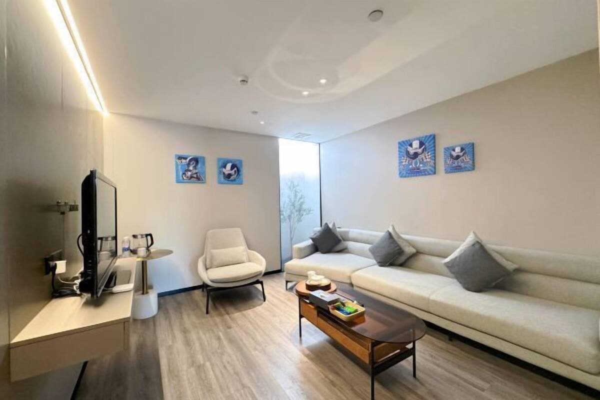 Una sala de estar moderna con sofá, sillón, mesa de centro y obras de arte en las paredes.