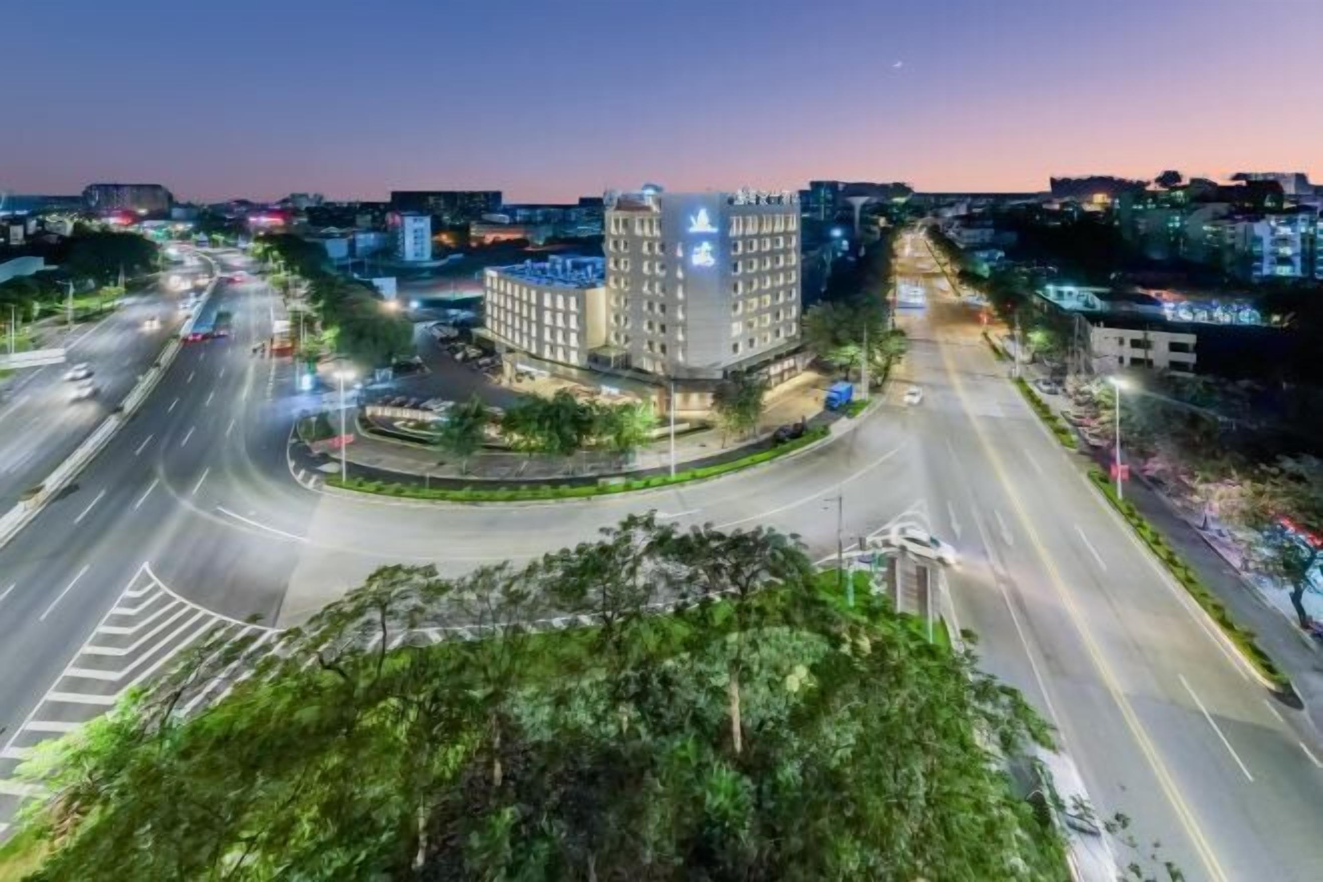 A multi-story hotel with a central courtyard, surrounded by a cityscape at dusk.