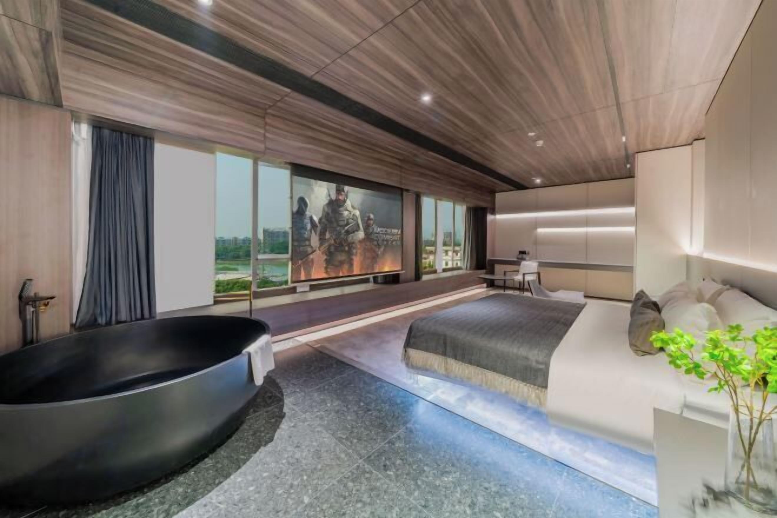 A modern hotel room with a large bed, a bathtub, and a large window offering a city view.