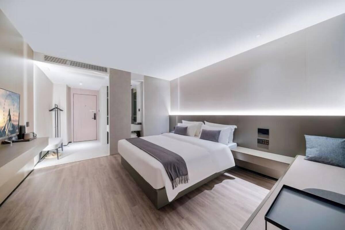 Una habitación de hotel moderna con una cama grande, mesitas de noche, un escritorio y un televisor.