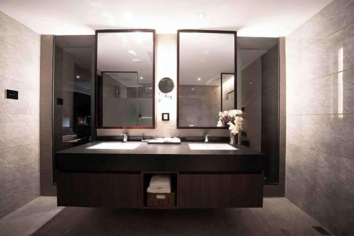 Un baño moderno con dos lavamanos, espejos grandes y un perchero para toallas.