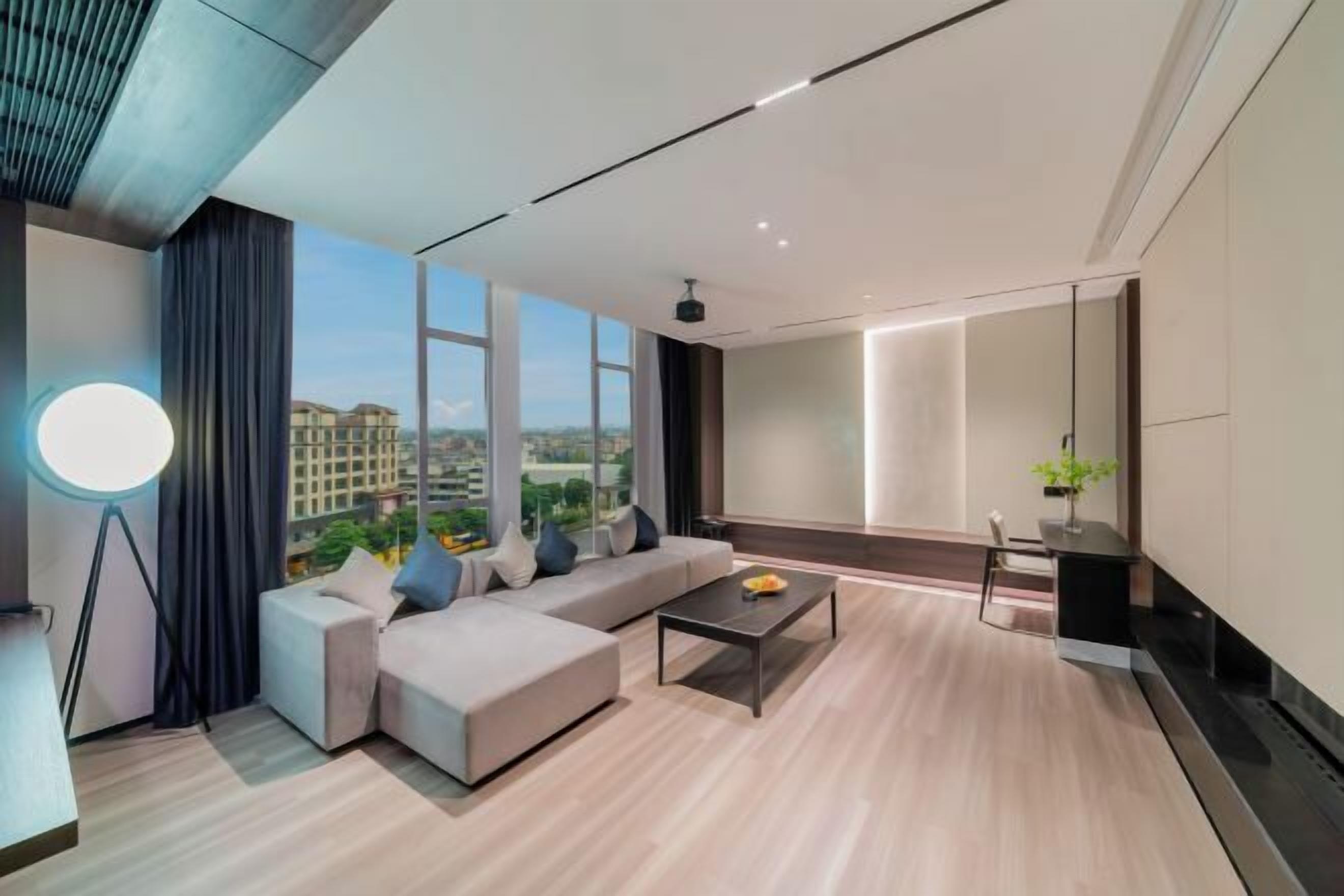 A modern living room with a sofa, coffee table, and a large window offering a city view.