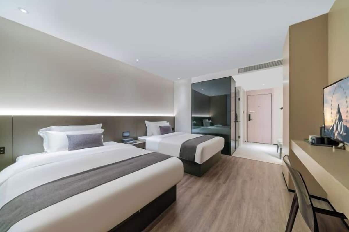Una habitación de hotel moderna con dos camas, un escritorio y un televisor.