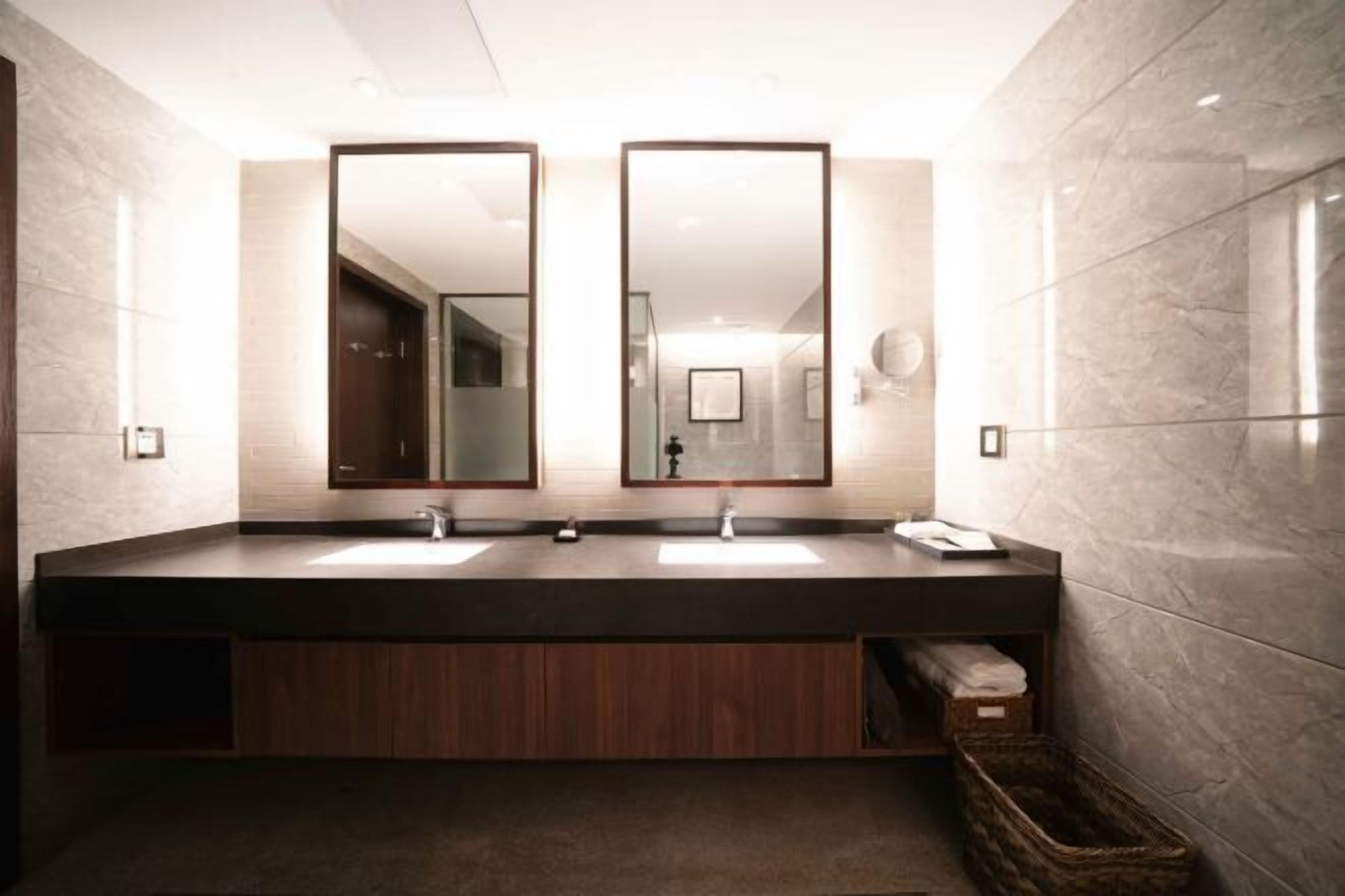A modern bathroom with two sinks, large mirrors, and a wooden vanity.