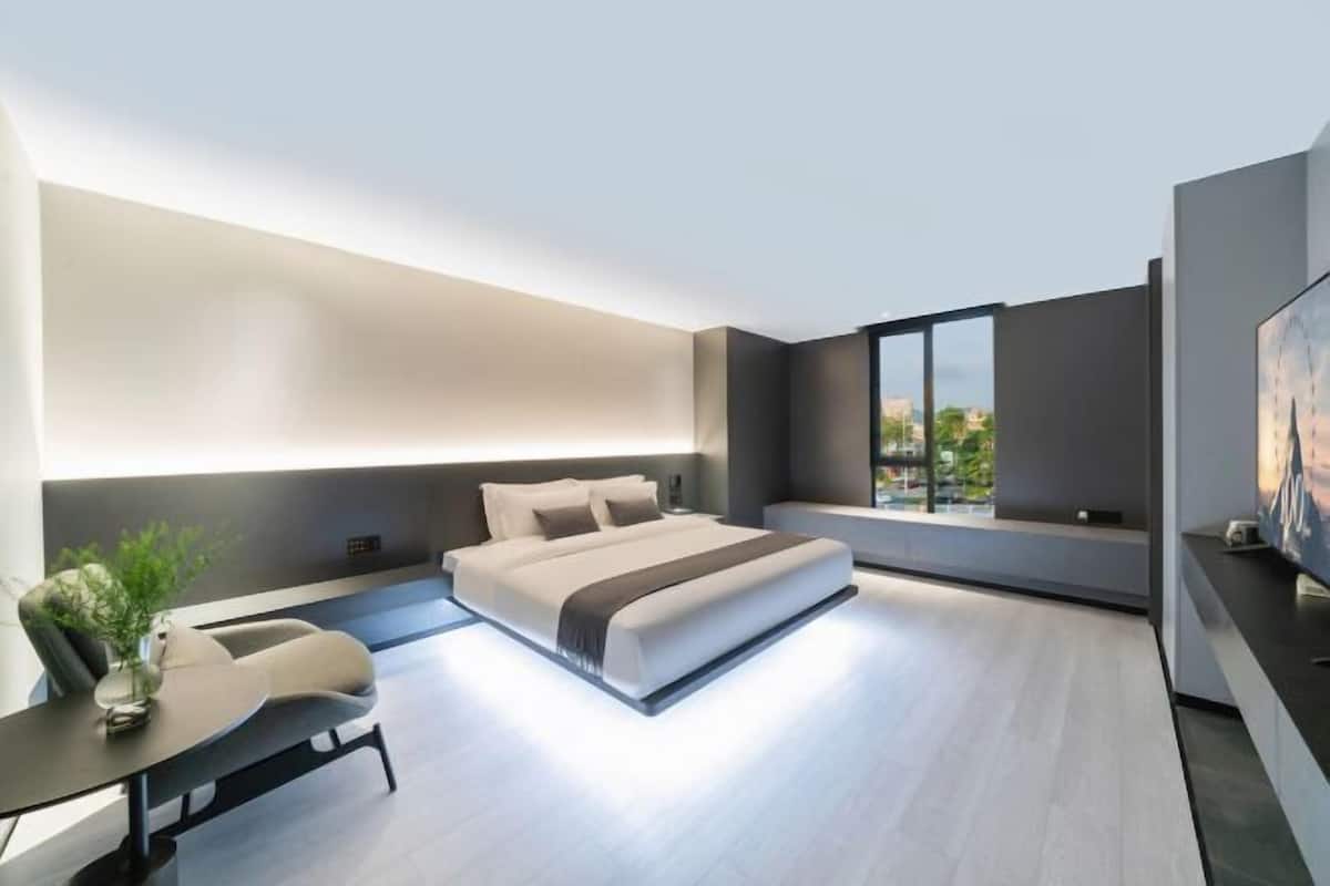 Un dormitorio moderno con una cama grande, un escritorio y un ventanal con vista a la ciudad.