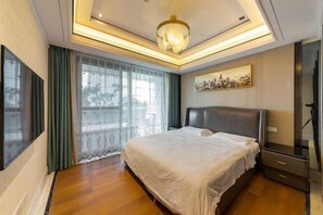 A modern bedroom with a large bed, a ceiling light fixture, a painting on the wall, and a window with curtains. - Sanya Xiyue Luxury Villa (Yalong Bay Forest Park Branch) (Sanya)