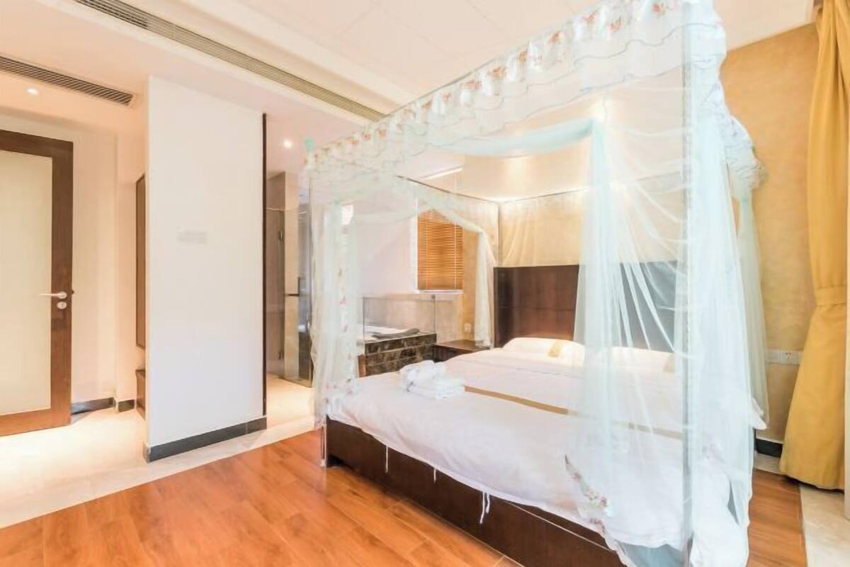 Un lit à baldaquin, un plancher en bois, une table de chevet et une commode.
