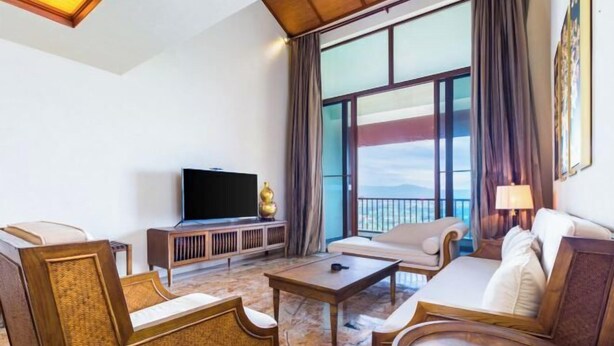A hotel room with a large window, a flat-screen TV, a sofa, a coffee table, and a decorative vase. - Sanya Xiyue Luxury Villa (Yalong Bay Forest Park Branch) (Sanya)
