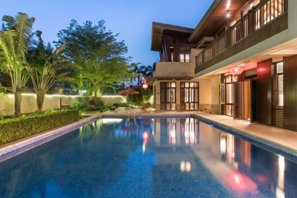 Un bâtiment moderne doté d’une piscine, entouré de verdure.