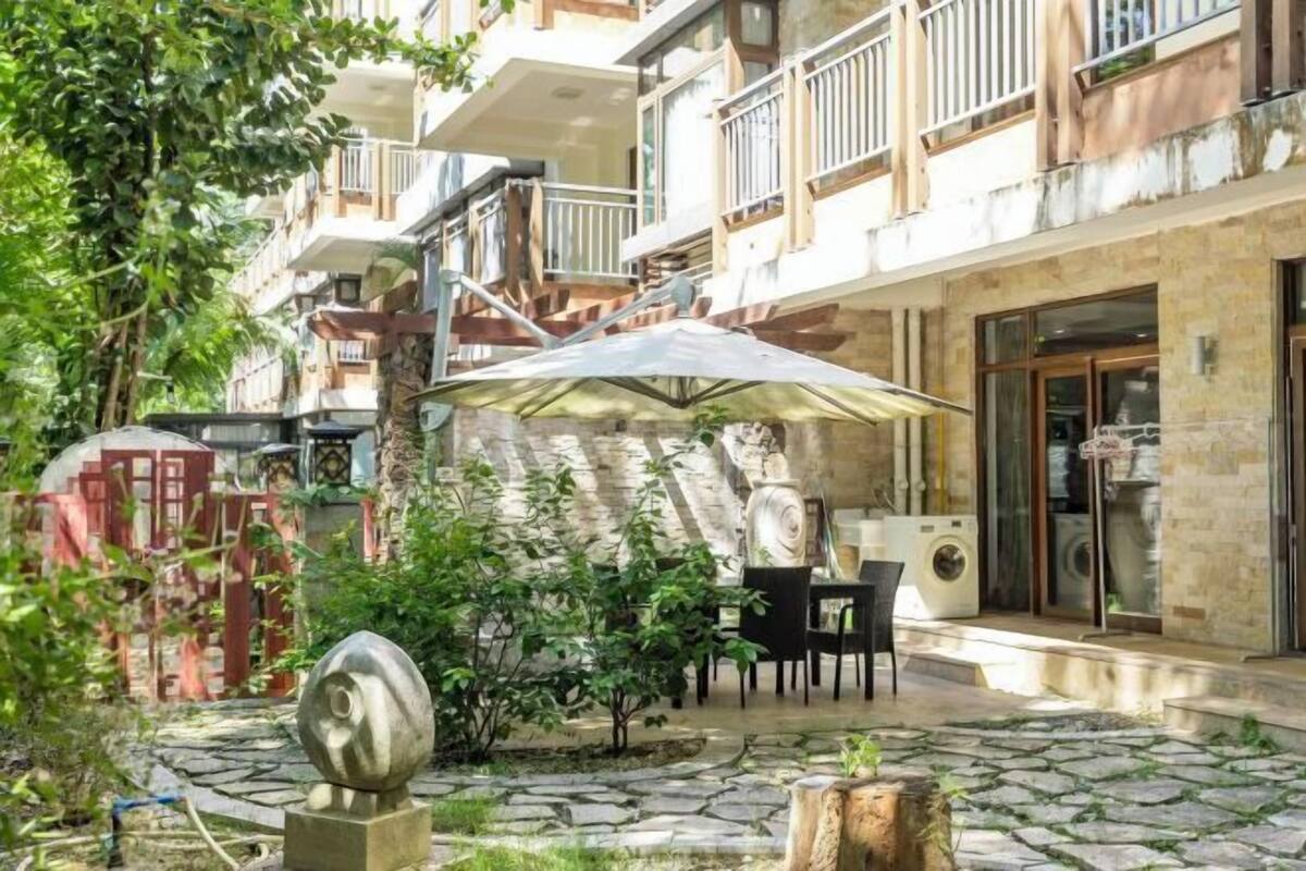Une cour avec un sol en pierre, une sculpture ronde et une table entourée de chaises, le tout abrité sous un grand parasol.