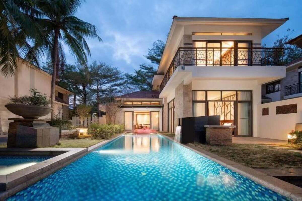 Une maison moderne à deux étages, dotée d’une piscine, d’un patio couvert et offrant une vue sur le paysage environnant.
