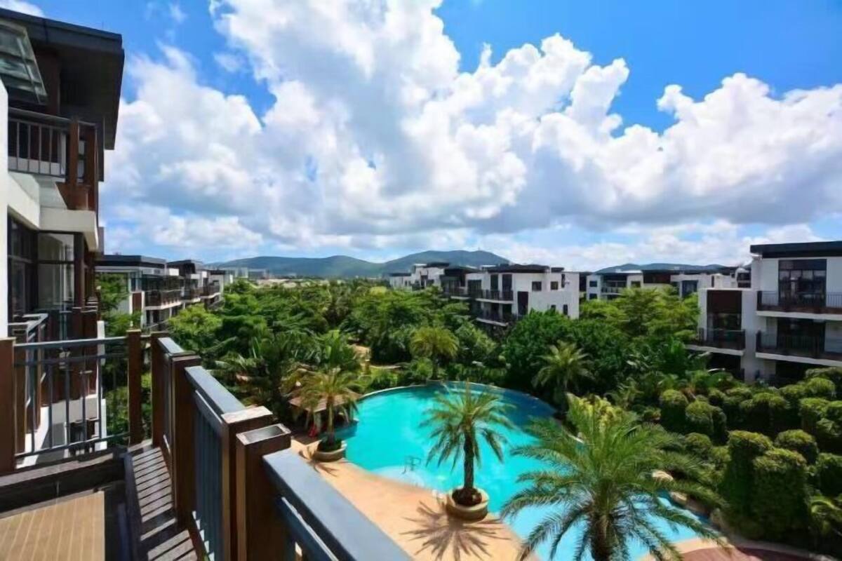Un quartier résidentiel avec des bâtiments modernes, une piscine entourée de verdure et un ciel dégagé.