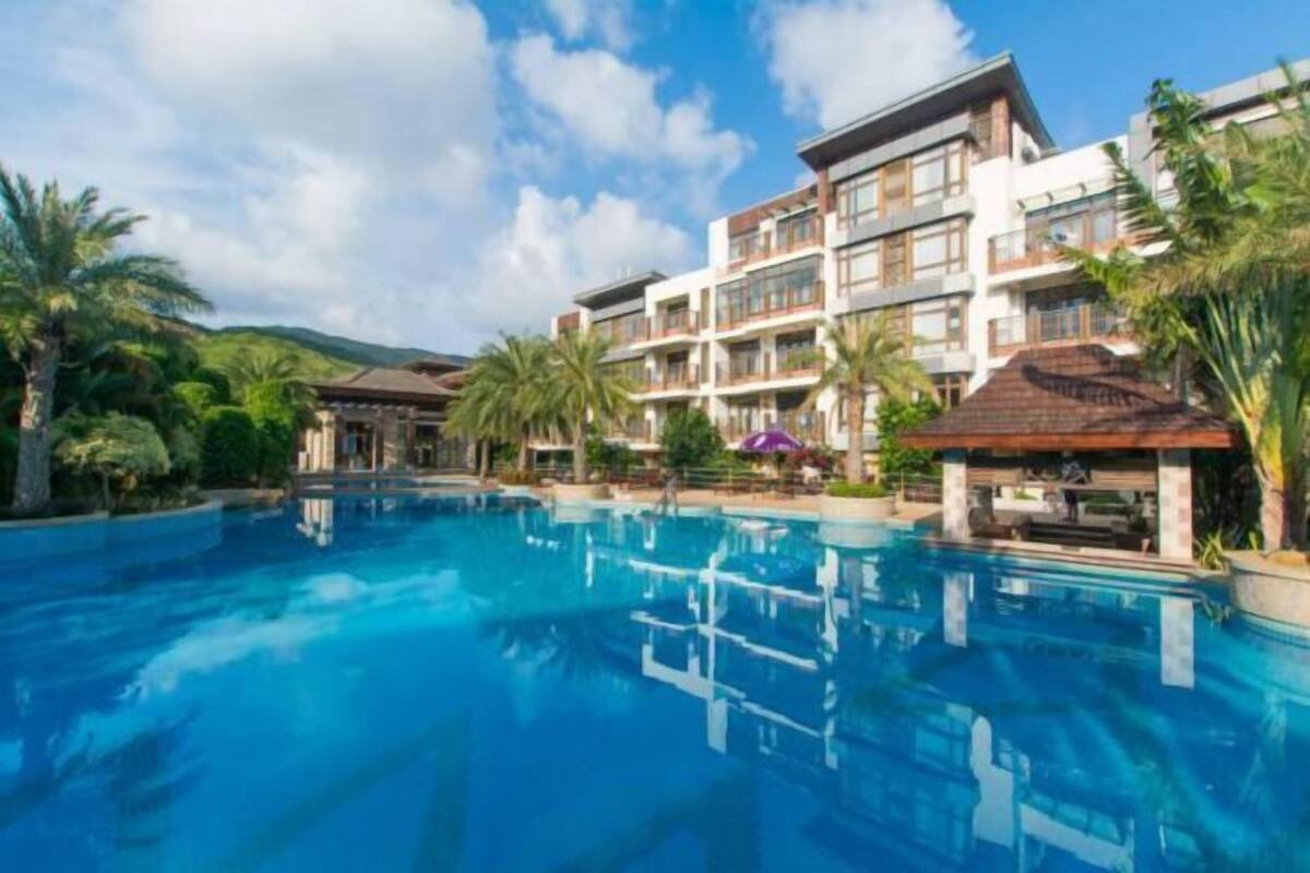 Un hôtel doté d’une piscine, de nombreux balcons et d’une végétation luxuriante.