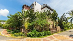 A modern building with a mix of architectural styles, surrounded by lush greenery and a paved walkway. - Sanya Xiyue Luxury Villa (Yalong Bay Forest Park Branch) (Sanya)