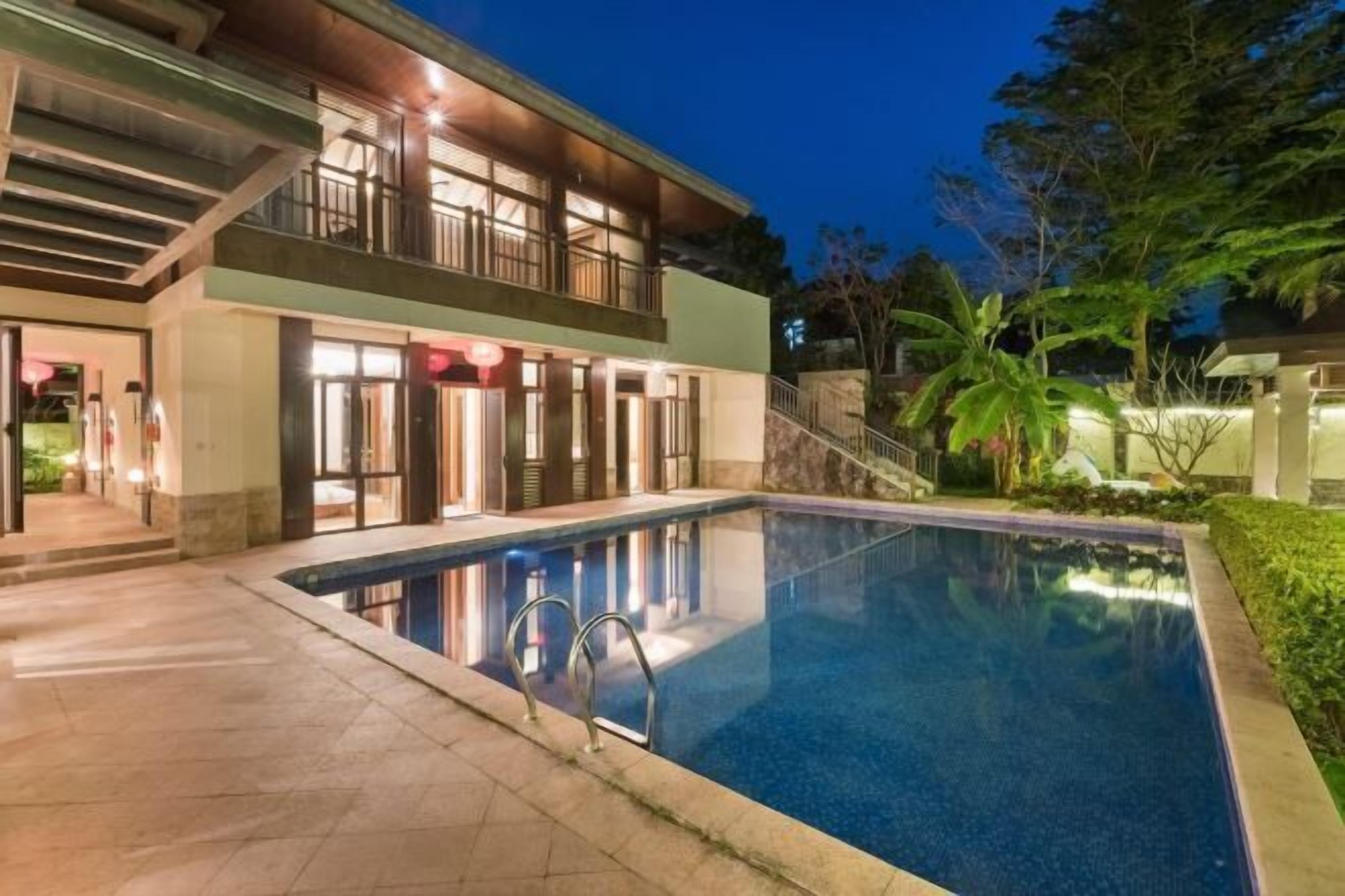 Un hotel moderno con piscina, un área exterior techada y una entrada bien iluminada.