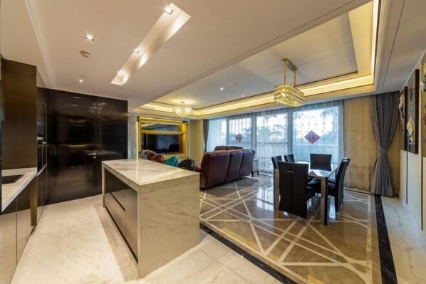 Een moderne woonkamer met een marmeren vloer, een centraal eiland, een eethoek met stoelen en een groot raam met gordijnen.