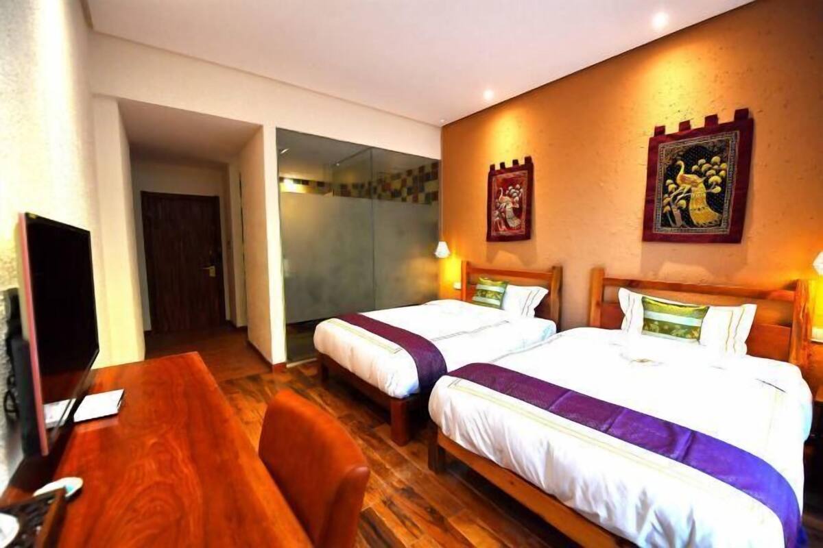 A hotel room with two beds, a wooden desk, and a television.