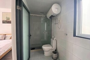Une salle de bain équipée de toilettes, d’une douche et d’un purificateur d’air fixé au plafond.