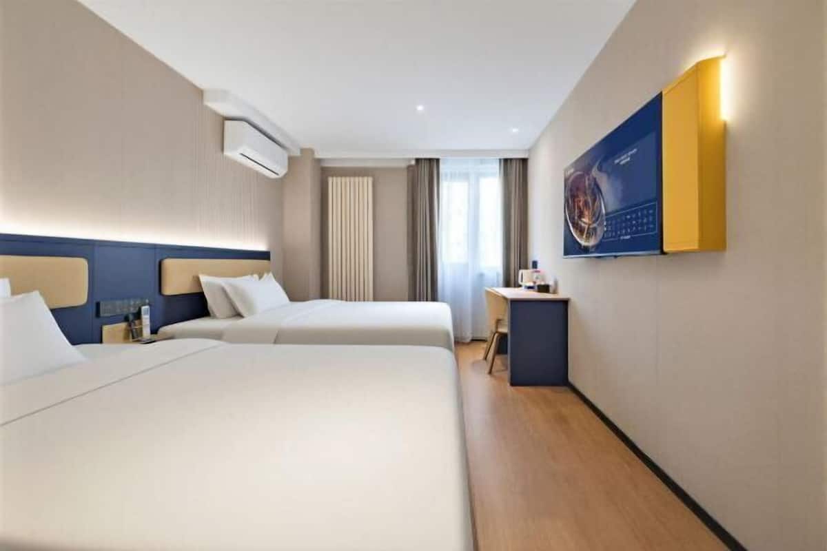 A hotel room with two beds, a desk, and a large poster on the wall.