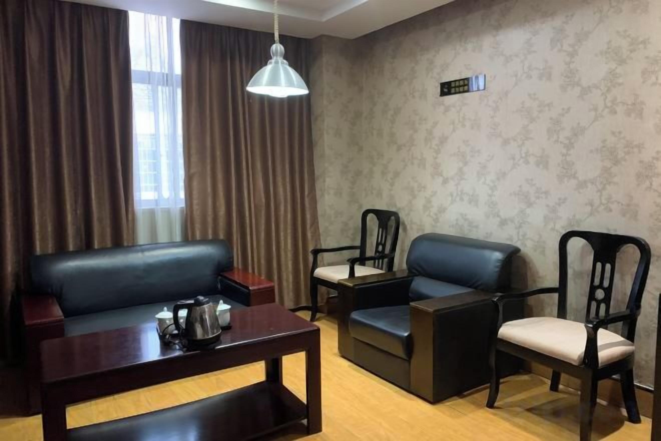 Una habitación con sofá, dos sillones, una mesa y una lámpara colgante.
