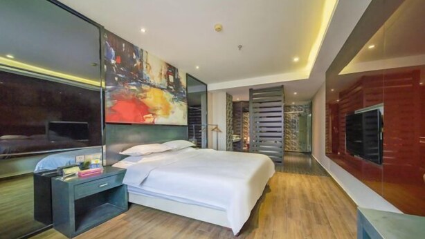 A modern hotel room with a large bed, a TV mounted on the wall, and a painting above the bed. - Dafuhao Hotel (Yichun Runda International Yuanzhou Gulou Square Branch) (Yichun)