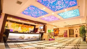 A hotel lobby with a reception desk, a digital screen, a large window, and a patterned floor. - Dafuhao Hotel (Yichun Runda International Yuanzhou Gulou Square Branch) (Yichun)