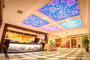 A hotel lobby with a reception desk, a digital screen, a large window, and a patterned floor. - Dafuhao Hotel (Yichun Runda International Yuanzhou Gulou Square Branch) (Yichun)