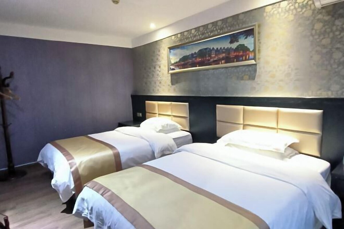 A hotel room with two beds, a painting on the wall, and a wooden floor.