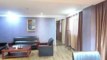 Una habitación de hotel con sofá, una mesita, una silla y un espejo.
