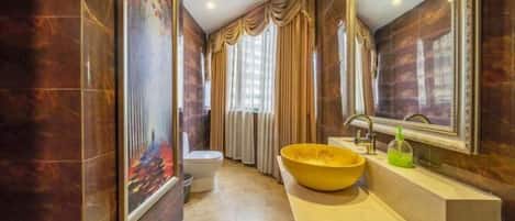 A bathroom with a large mirror, a yellow sink, and a painting on the wall.