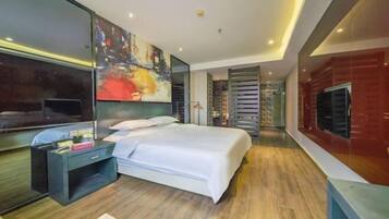 Una habitación de hotel moderna con una cama grande, un escritorio, un televisor y un cuadro en la pared.