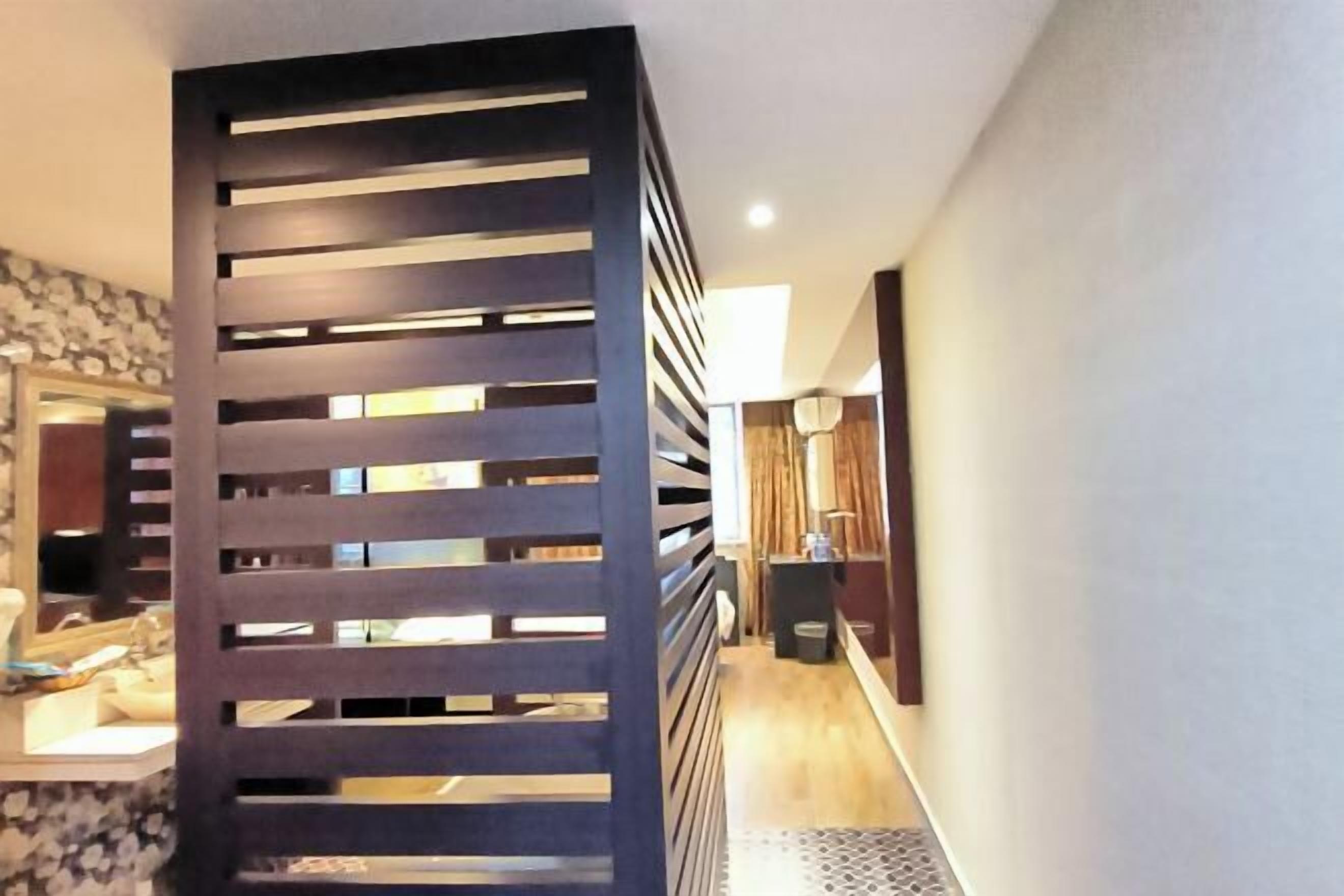 Un pasillo de diseño moderno con un separador de madera con listones horizontales.