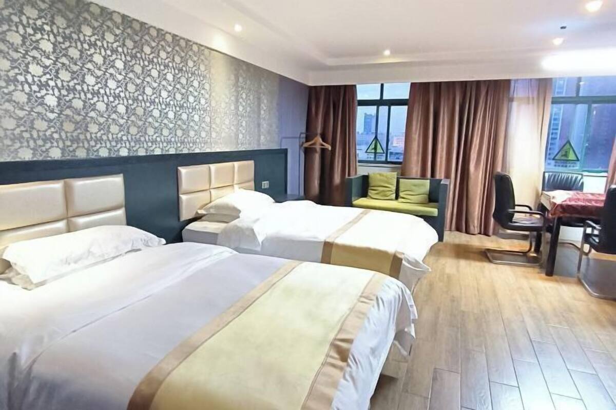 A hotel room with two beds, a desk, and a view of the city.