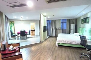 Habitación de hotel con cama, escritorio, silla, una mesita con bandeja y ventana con cortinas.