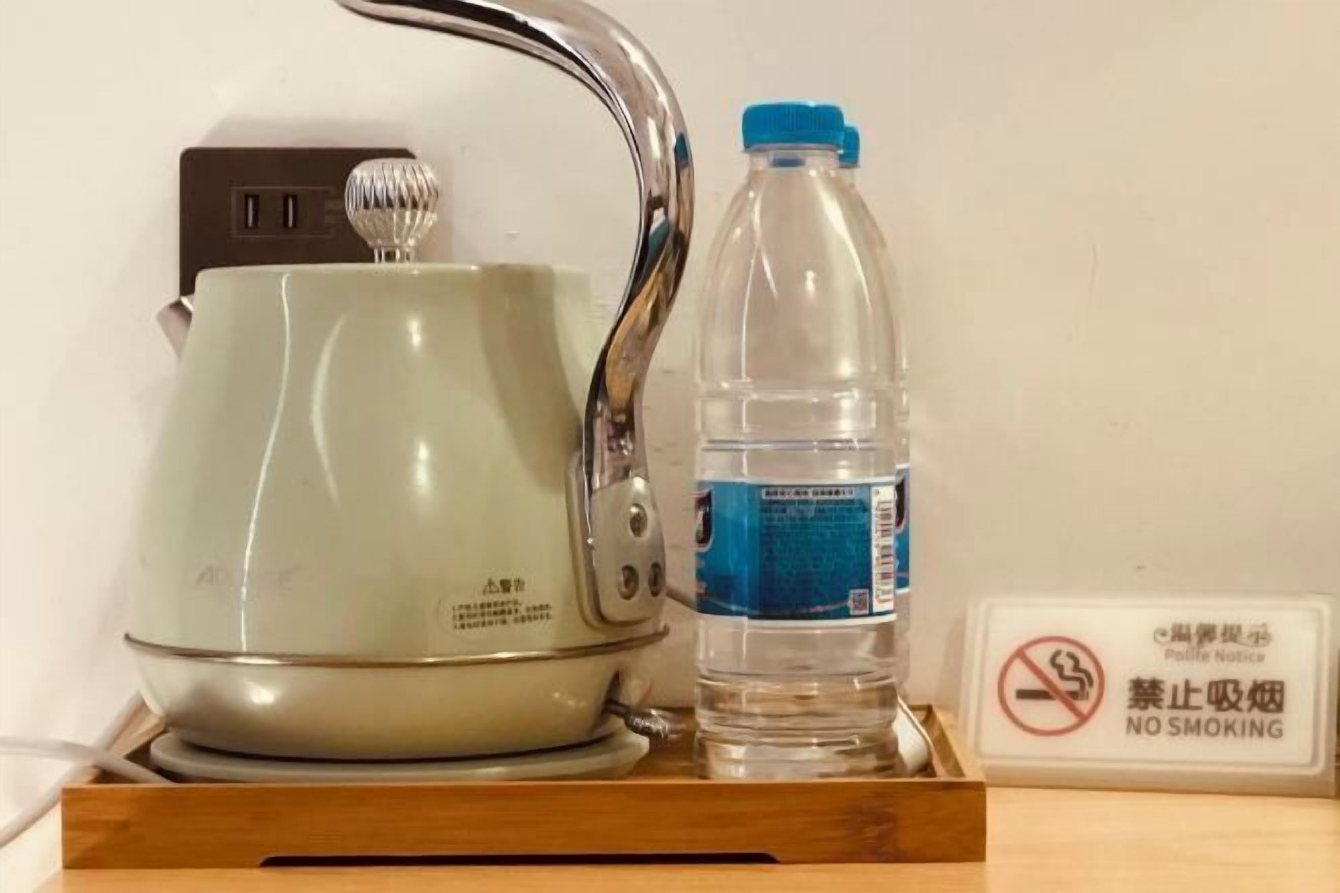 A kettle, a water bottle, and a no smoking sign on a wooden tray.
