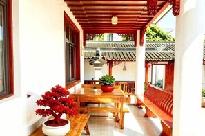 A traditional wooden table with a potted plant, a bench, and a view of a traditional building with a tiled roof. - Zhouzhuang Farmhouse (Zhouzhuang Ancient Town Branch) (Kunshan)