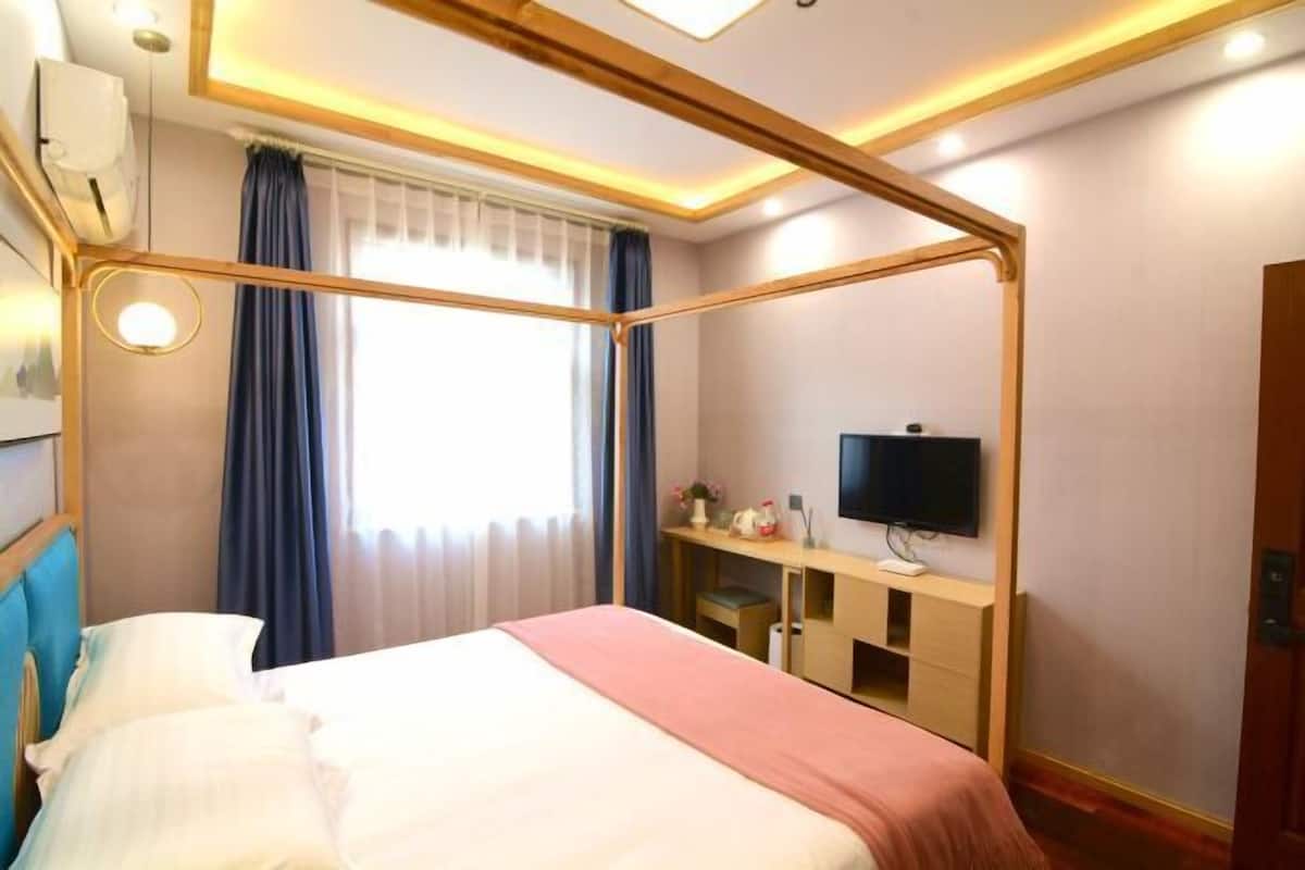 Een hotelkamer met een bed, een bureau, een televisie en een raam met gordijnen.