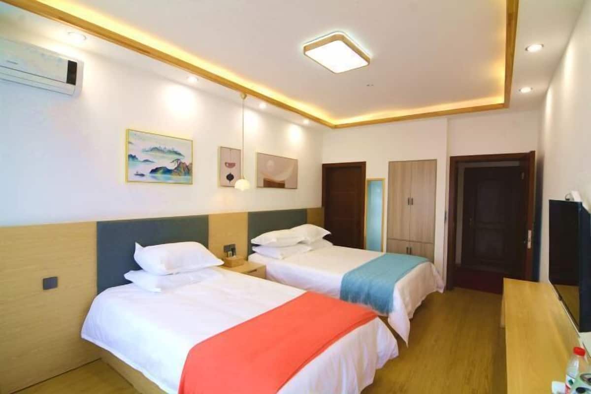 Een hotelkamer met twee bedden, een bureau, een televisie en kunst aan de muur.