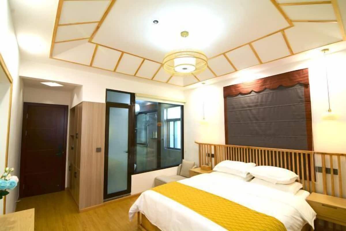 Een hotelkamer met een bed, nachtkastje, lamp en uitzicht buiten door een glazen deur.