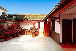 A traditional courtyard with tiled roofs, potted plants, and a wooden door. - Zhouzhuang Farmhouse (Zhouzhuang Ancient Town Branch) (Kunshan)