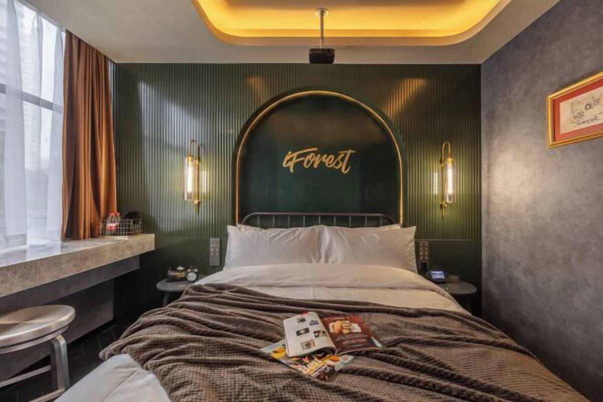 A hotel room with a bed, a desk, and a window with curtains.