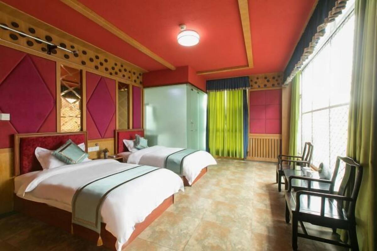 Quarto de hotel com duas camas, uma escrivaninha e cadeiras.