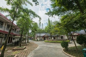 A courtyard with buildings, trees, and a paved walkway. - Cuiyuezhuang Countryside Hotel (Dujiangyan)