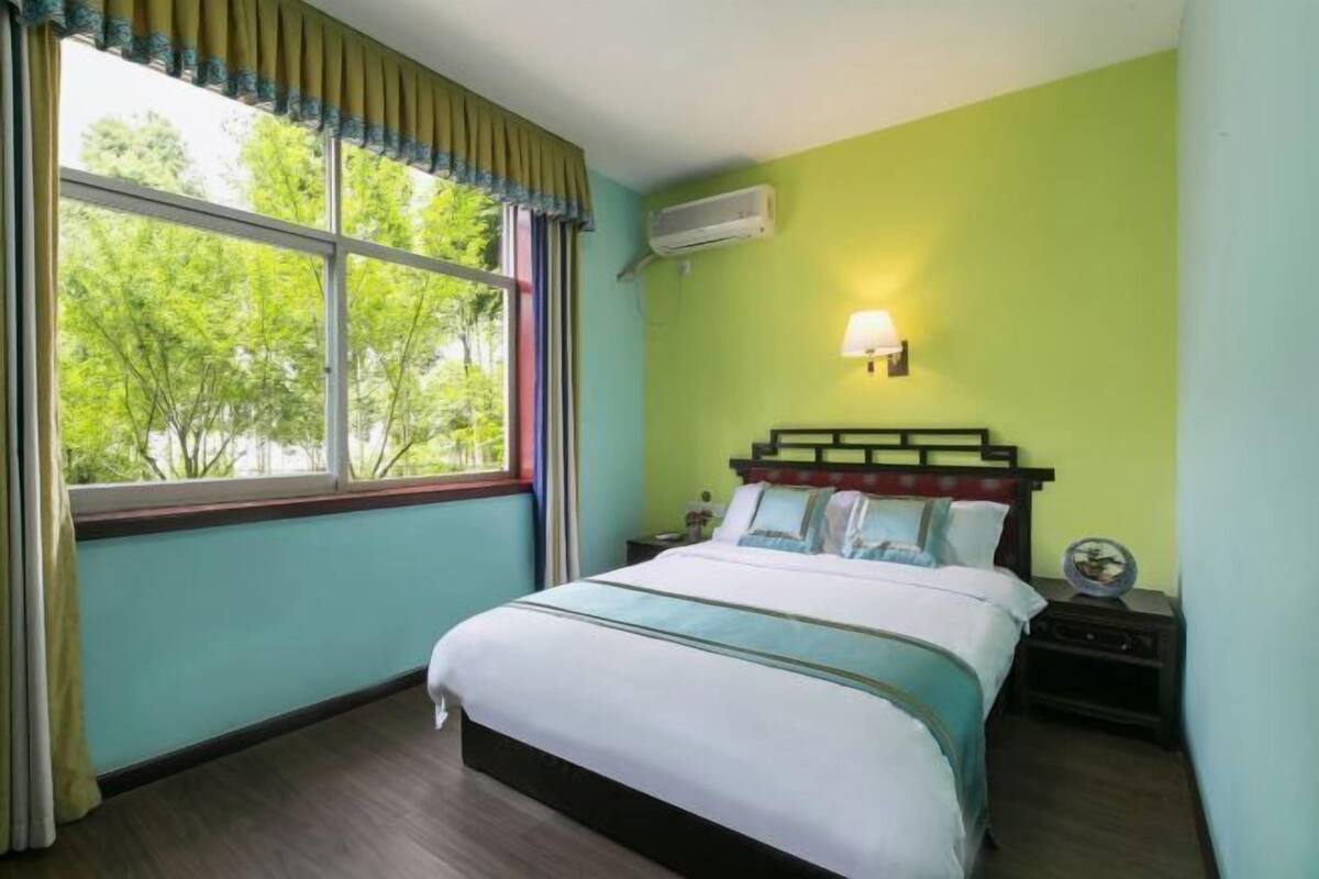 Quarto com cama, mesa de cabeceira, luminária e aparelho de ar condicionado.