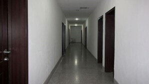 A long, narrow hallway with a polished floor and white walls. - Industry Hotel (Zhaoyuan)