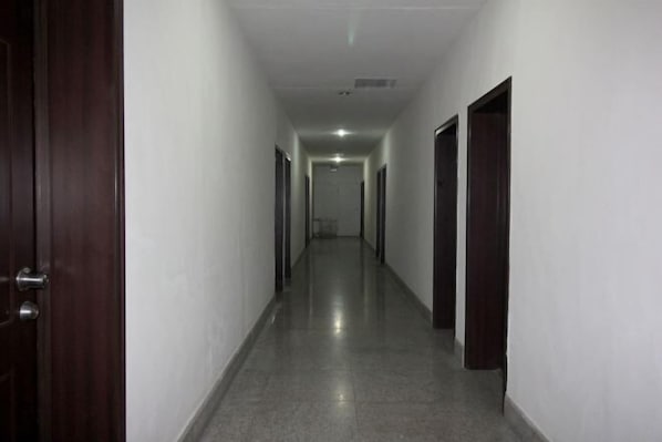 A long, narrow hallway with a polished floor and white walls. - Industry Hotel (Zhaoyuan)