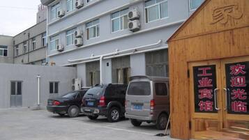 Un bâtiment doté d’un espace de stationnement, d’une structure en bois avec des panneaux indicateurs et d’un immeuble à plusieurs étages équipé de climatiseurs.